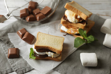 Delicious marshmallow sandwich with bread and chocolate on white wooden table, closeup