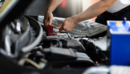 Auto mechanic worker checking and changing car battery. Car maintenance and auto service garage...