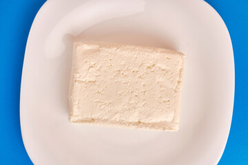 A slice of sour milk cheese on a white plate.