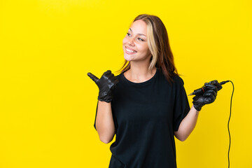 Tattoo artist Russian woman isolated on yellow background pointing to the side to present a product