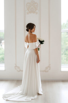 brunette bride in a tight wedding dress in a bright studio