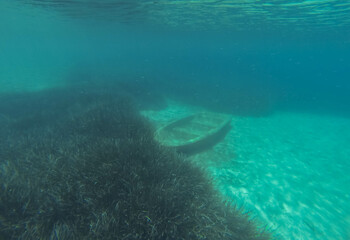 The old boat is abandoned and flooded in shallow water.