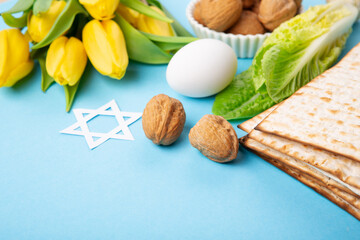 Fototapeta na wymiar Passover Greeting Card with Matzah, Waluts and Yellow Tulip Flowers on Blue Background.