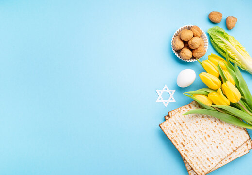 Passover Greeting Card with Matzah, Waluts and Yellow Tulip Flowers on Blue Background.