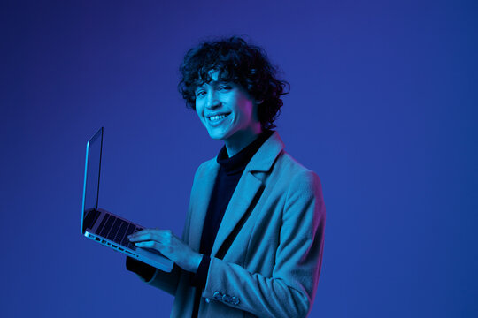 A man with a laptop in his hands and a jacket, smile, blue light glasses, Blue Perennial color, cyber security, technology, open laptop copy space, trendy neon, freelancer, purple light