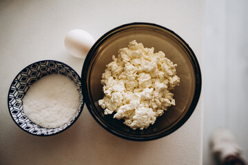 cottage cheese, egg and salt in a black glass bowl on a white table. making breakfast with your own hands