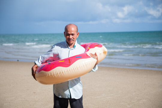 Portrait one mature elderly asian man enjoying summer beach vacations. Bright swimming inflatable ring