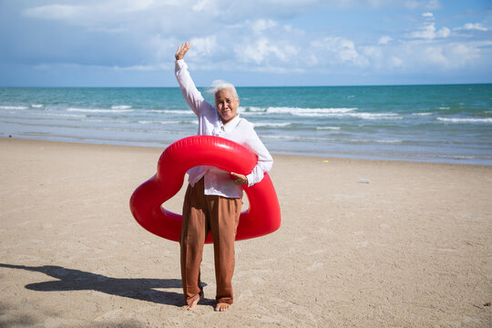 Portrait one mature elderly asian women enjoying summer beach vacations. Bright swimming inflatable ring