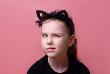 Portrait of a moody girl, a suspicious look, conceived, isolated on a pink background with space for text