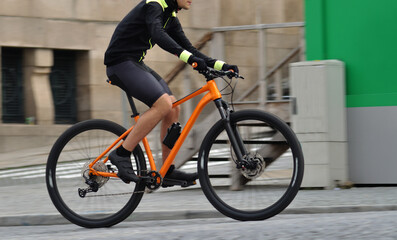 Person riding a orange bicycle on a city street, motion blur, speed