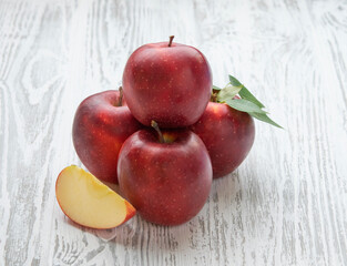 Sweet red apples with leaves on a white wooden background. Farm healthy and eco-friendly fruits. Rustic style.