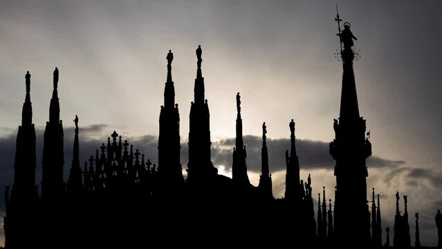 Cathedral of the Nativity of Saint Mary in Milan, Time Lapse at Sunrise with Fast Clouds and Dark Silhouette statue on top of Duomo, Italy