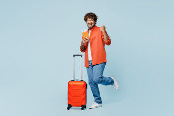 Traveler winner Indian man wear casual clothes hold suitcase passport ticket isolated on plain...