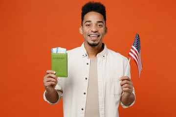 Traveler fun man wear casual clothes hold passport ticket American flag isolated on plain orange...