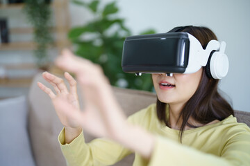 Young Asian woman gamer wearing virtual reality touching air during the VR experience  Future home technology player hobby playful enjoyment concept.