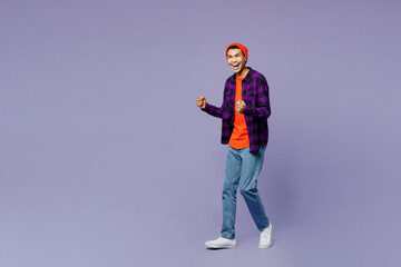 Full body young man of African American ethnicity wear casual shirt orange hat doing winner gesture celebrate clenching fists say yes isolated on plain pastel purple color background studio portrait.