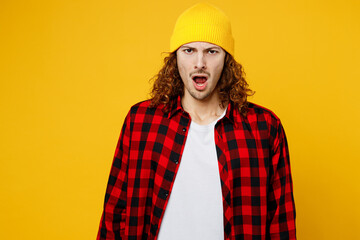 Young indignnat dissatisfied displeased caucasian man wearing red checkered shirt white t-shirt hat look camera with opened mouth isolated on plain yellow background studio portrait Lifestyle concept