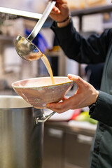 Fototapeta na wymiar chef cooking tasty soup in big pot on restaurant kitchen
