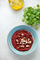 Turquoise bowl with beetroot paste, vertical shot on a light-beige stone background, high angle view