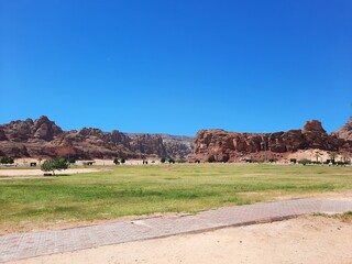 A beautiful daytime view of a winter park in Al-Ula, Saudi Arabia. The park is surrounded by ancient hills.