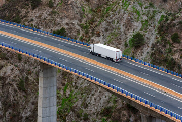 Truck with a refrigerated semi-trailer driving on a highway bridge, top view.