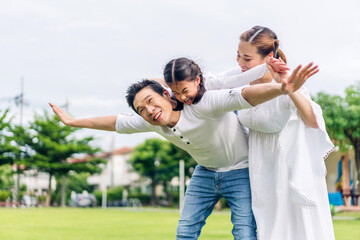 Portrait of enjoy happy love asian family father and mother holding hug cute little asian girl child smiling play and having fun moments good time in summer park at home