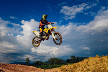 Fototapeta na wymiar motocross rider jumping up the hill with a sky background