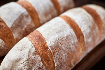 Freshly baked homemade wheat loaves on wooden background. Close-up, selective focus