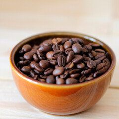 Fototapeta premium close-up of brown coffee beans in a bowl, coffee beans background, coffee beans in a bowl on wooden table, space for text, roasted coffee beans, square design