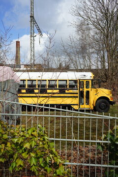 Typischer amerikanischer Schulbus in Gelb und Weiß bei Sonnenschein hinter einem Zaun im Gewerbegebiet in Detmold am Teutoburger Wald im Lipperland in Ostwestfalen-Lippe