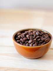 close-up of brown coffee beans in a bowl, coffee beans background, coffee beans in a bowl on wooden table, space for text, roasted coffee beans