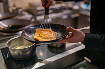 man chef hand cooking one big Ravioli with sauce on restaurant kitchen