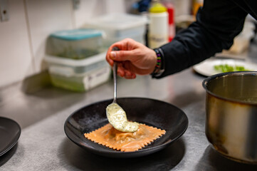 man chef hand cooking one big Ravioli with sauce on restaurant kitchen
