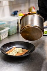 man chef hand cooking one big Ravioli with sauce on restaurant kitchen