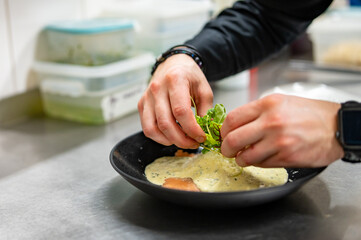 man chef hand cooking one big Ravioli with sauce on restaurant kitchen