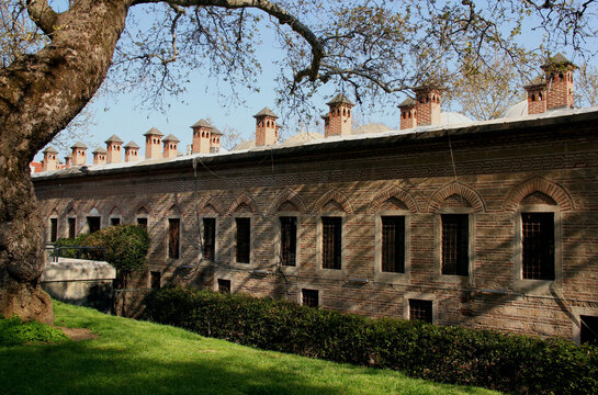 Side view of the exterior of the Koza Han building with multiple towers and a tree in the foreground in Bursa, Turkey