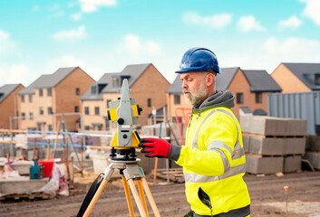 Surveyor builder site engineer with theodolite total station at construction site outdoors during...