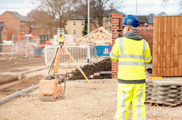 Surveyor builder site engineer with theodolite total station at construction site outdoors during...