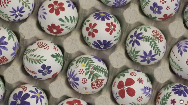 Colorful Easter eggs in the tray rotate. Happy Easter holiday concept. Easter egg is traditional symbol for religious holiday. Christian celebration traditions, vertical video top view slow motion 