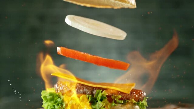 Super slow motion of stacking cheeseburger pieces. Camera in motion. Filmed on high speed cinema camera, 1000 fps. Placed on high speed cine bot. Fire on background.
