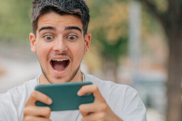 scared or surprised young man or student looking at mobile phone