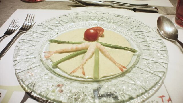 still view of a fancy salad meal dish in western luxury arrangement style with shrimps and asparagus tomato and sauce on glass place with spoon and fork