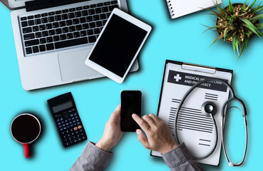 Top view of doctor hand writing department writes a note and uses a calculator to calculate expenses - income on a wooden table. Health and medical concept.