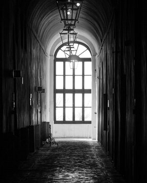 Window with dim light in a corridor of an old castle. Photography in black and white, with suspense and calm