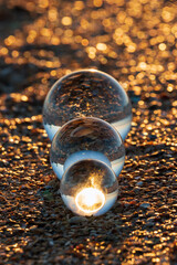 Glass lens globes on sandy beach on sandy beach at sunset close up. Beauty, fancy, family, evolution, increase and growth, rise and increment concept.