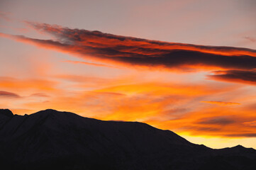 silhouette of the mountain and the sunset sky. Colorful red sunset, in the foreground the silhouette of the ridge of the rocky mountains