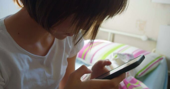 Teenage girl checking social media messages on smartphone after awakening.