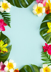 Summer background with tropical orchid flowers and green tropical palm leaves on light background. Flat lay, top view.