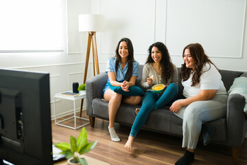 Relaxed women friends in pajamas watching movies