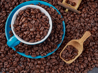Cup of steaming hot coffee with coffee beans, coffee grinder, and coffee beans bag in background.